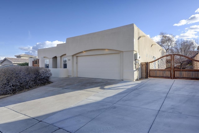 view of home's exterior featuring stucco siding, concrete driveway, an attached garage, and a gate