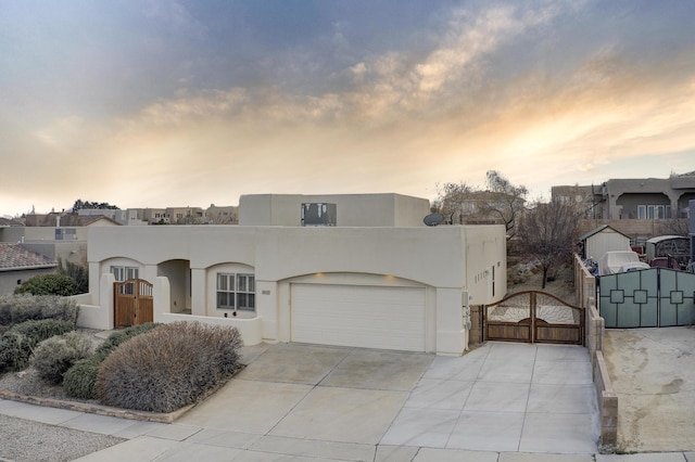 view of front of property with stucco siding, a gate, fence, concrete driveway, and a garage