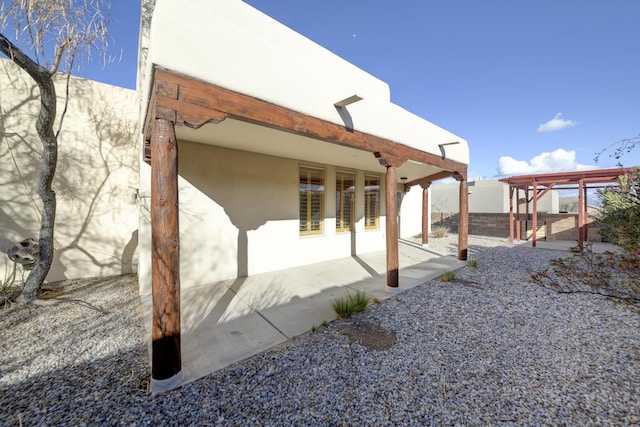 view of home's exterior with stucco siding, a pergola, and a patio