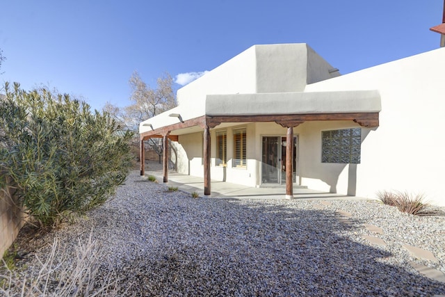 rear view of house featuring a patio area and stucco siding