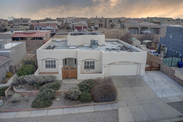 view of front facade featuring a residential view, stucco siding, concrete driveway, and fence