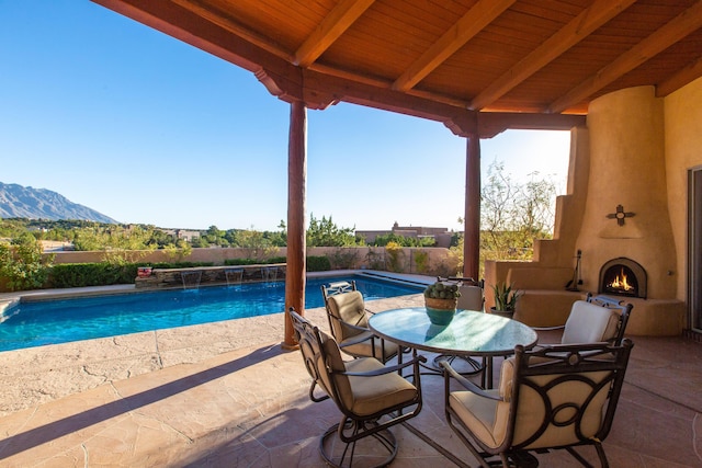 view of patio / terrace with a fenced in pool, a mountain view, and a large fireplace