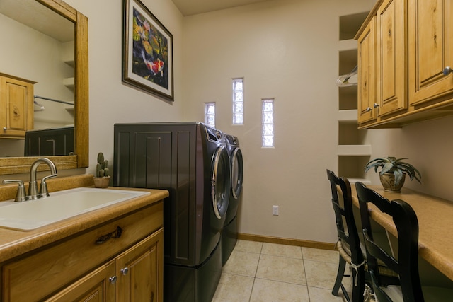 washroom with light tile patterned floors, baseboards, washing machine and clothes dryer, cabinet space, and a sink