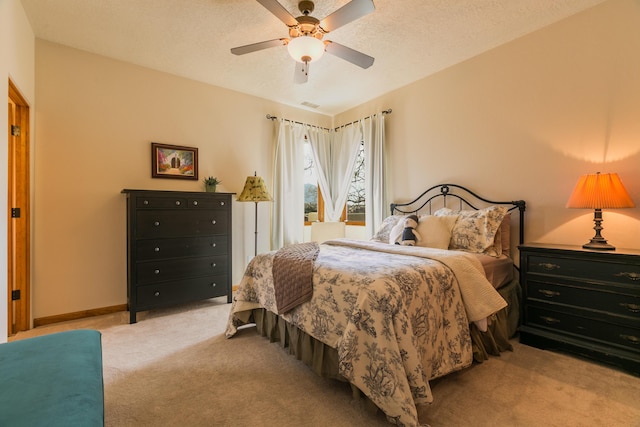 bedroom with visible vents, baseboards, carpet floors, ceiling fan, and a textured ceiling