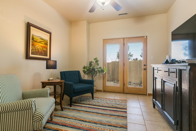 living area featuring visible vents, baseboards, light tile patterned flooring, and a ceiling fan