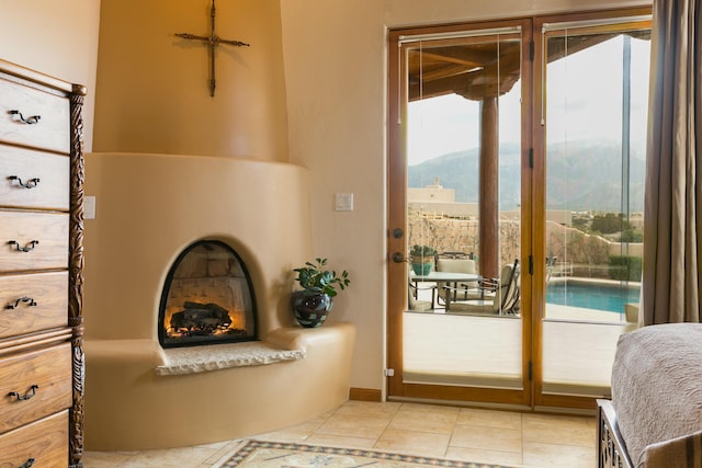 doorway with light tile patterned flooring, a mountain view, and a warm lit fireplace