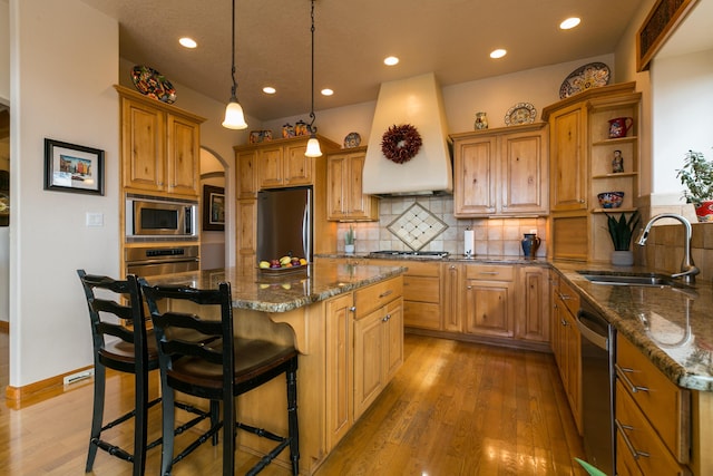 kitchen featuring custom range hood, open shelves, a center island, light wood-style floors, and appliances with stainless steel finishes