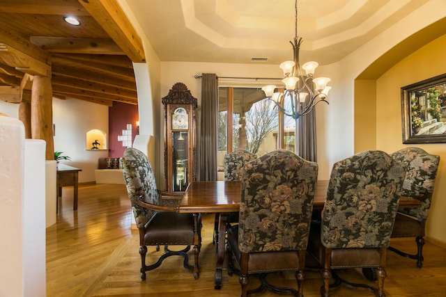 dining area featuring beamed ceiling, a notable chandelier, wood finished floors, and visible vents