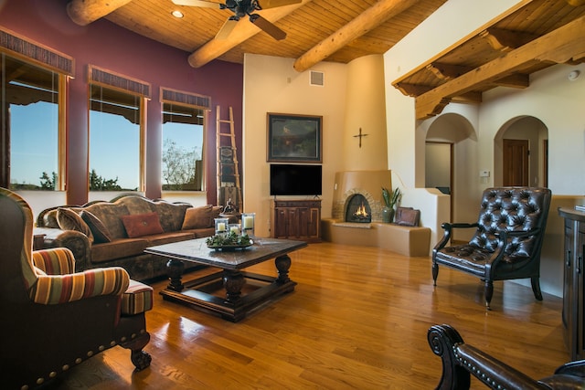 living room with a ceiling fan, wood finished floors, visible vents, beam ceiling, and wooden ceiling