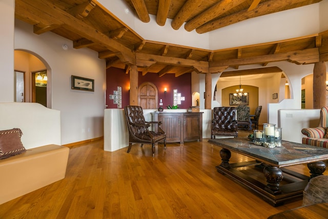 interior space featuring beam ceiling, wood finished floors, arched walkways, an inviting chandelier, and wooden ceiling