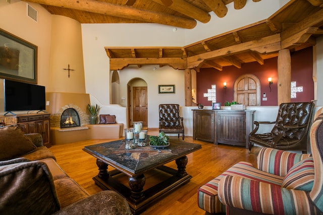 living area with wood finished floors, beamed ceiling, visible vents, wooden ceiling, and a brick fireplace