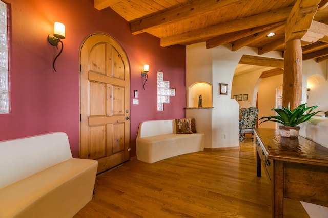 foyer featuring arched walkways, beam ceiling, wood ceiling, and wood finished floors