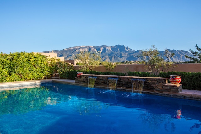 view of swimming pool featuring a fenced in pool, a mountain view, and fence