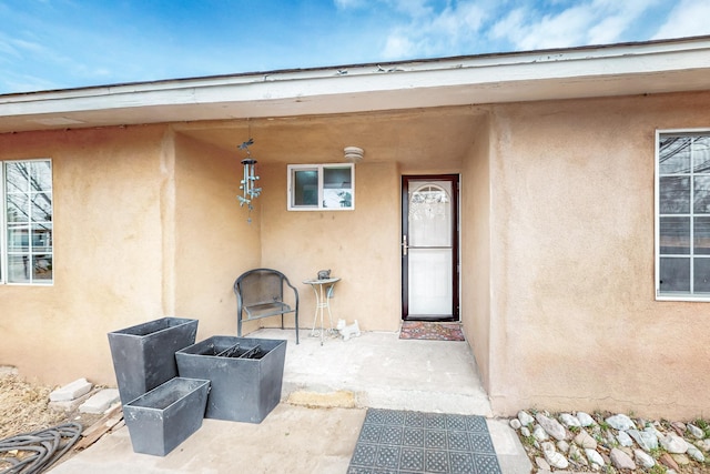 view of exterior entry with a patio and stucco siding