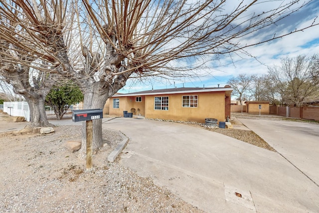 view of front of property featuring stucco siding, driveway, and fence