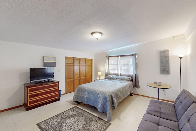 bedroom with baseboards, a closet, light floors, and a textured ceiling