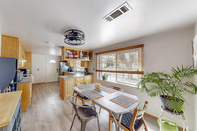 dining area featuring light wood finished floors, visible vents, and baseboards