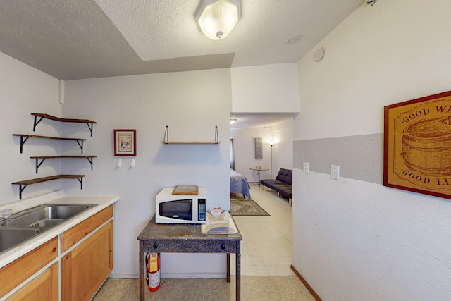 kitchen featuring white microwave, a textured ceiling, light countertops, and open shelves