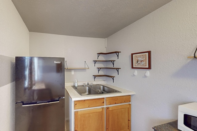 kitchen featuring a sink, open shelves, freestanding refrigerator, light countertops, and white microwave