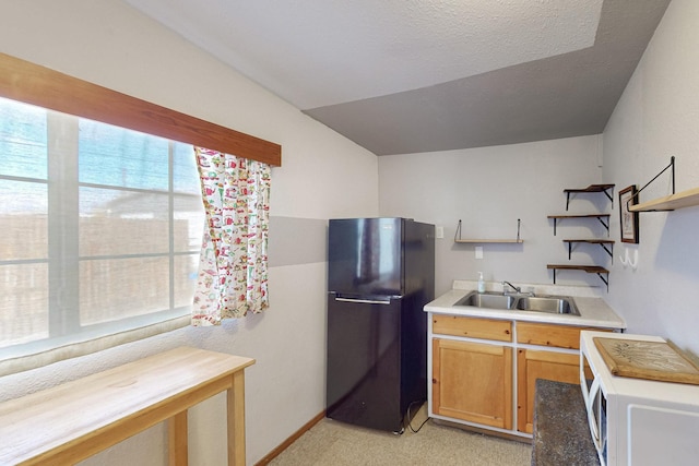 kitchen with white microwave, open shelves, freestanding refrigerator, a sink, and light countertops