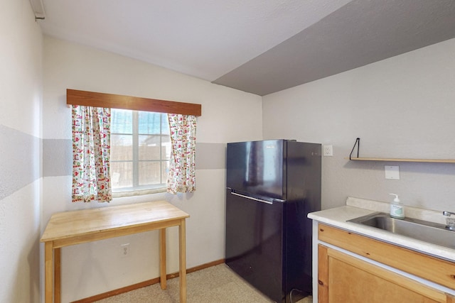 kitchen featuring a sink, baseboards, light countertops, and freestanding refrigerator