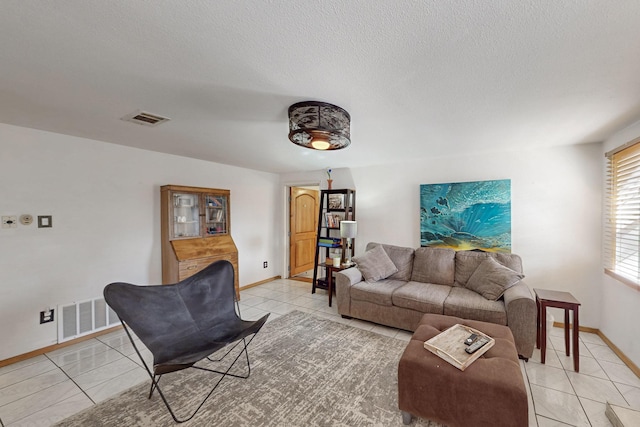 living room featuring light tile patterned floors, visible vents, and a textured ceiling