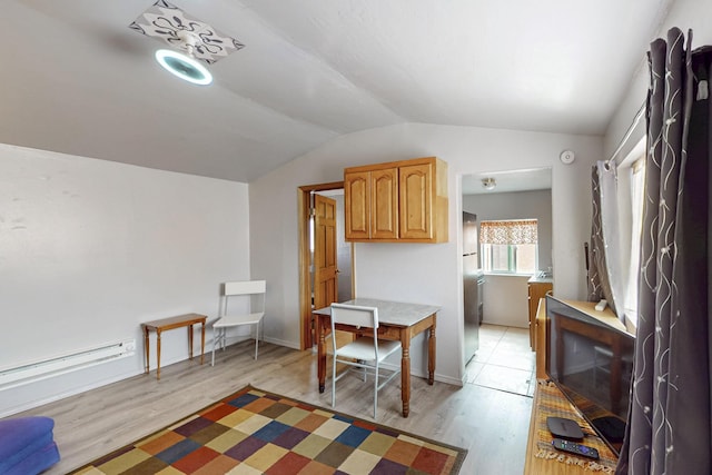 dining area with vaulted ceiling, light wood-style floors, and baseboards