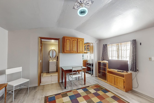 office featuring baseboards, light wood-style flooring, and vaulted ceiling