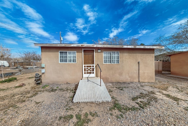 back of property featuring fence and stucco siding