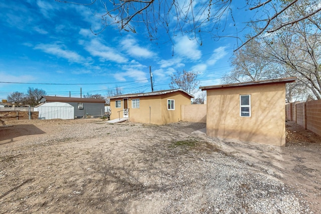 back of house featuring stucco siding, an outdoor structure, and a fenced backyard