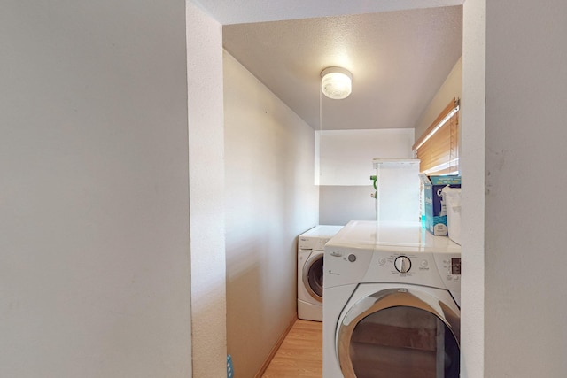 clothes washing area featuring washer and clothes dryer, laundry area, and light wood-style flooring