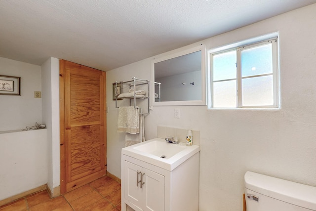 bathroom with vanity, baseboards, tile patterned flooring, a textured ceiling, and toilet