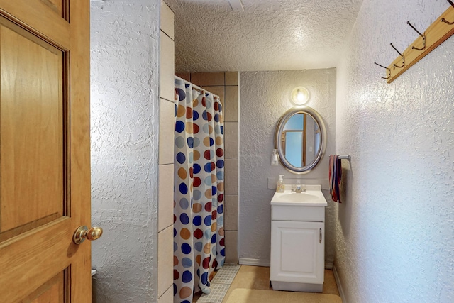 bathroom with vanity, a textured wall, and a textured ceiling