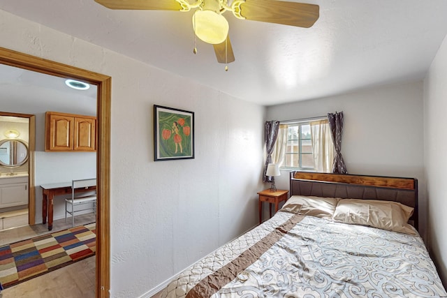 bedroom featuring a ceiling fan, a textured wall, and light wood finished floors