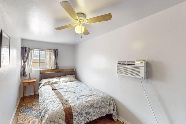 bedroom with a wall unit AC, a ceiling fan, and baseboards