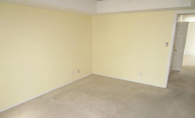 unfurnished room featuring light carpet and baseboards