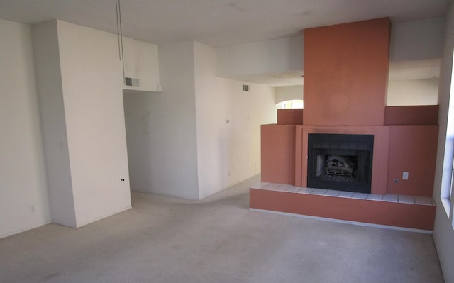 unfurnished living room with visible vents, carpet floors, and a tile fireplace