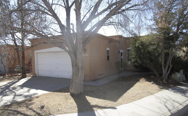 view of side of property featuring crawl space, concrete driveway, a garage, and stucco siding