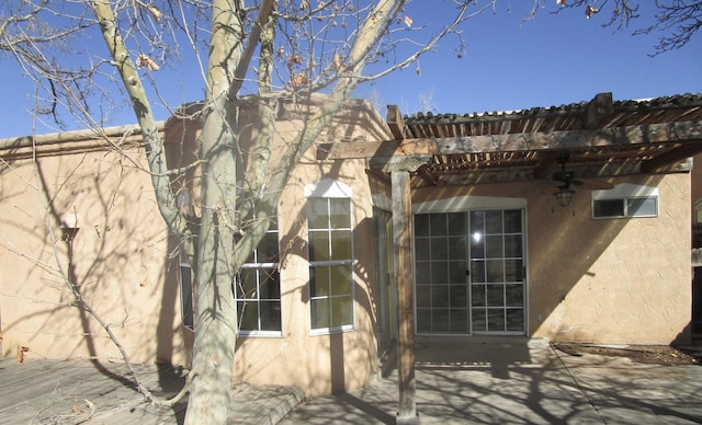 view of home's exterior with stucco siding, a patio, a ceiling fan, and a pergola