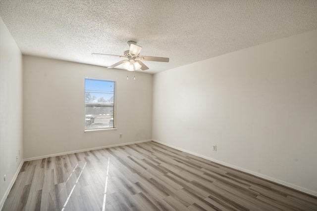 unfurnished room featuring a ceiling fan, wood finished floors, baseboards, and a textured ceiling