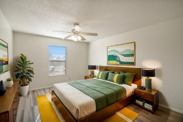 bedroom featuring a textured ceiling, a ceiling fan, baseboards, and wood finished floors