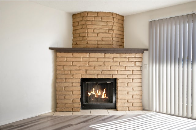 room details featuring baseboards, a brick fireplace, and wood finished floors