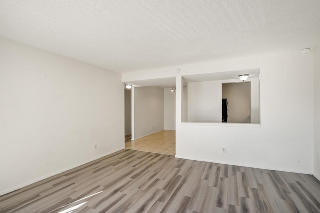 spare room featuring wood finished floors, baseboards, and a textured ceiling