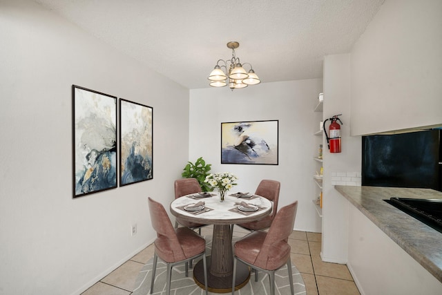 dining area featuring baseboards, a textured ceiling, an inviting chandelier, and light tile patterned flooring