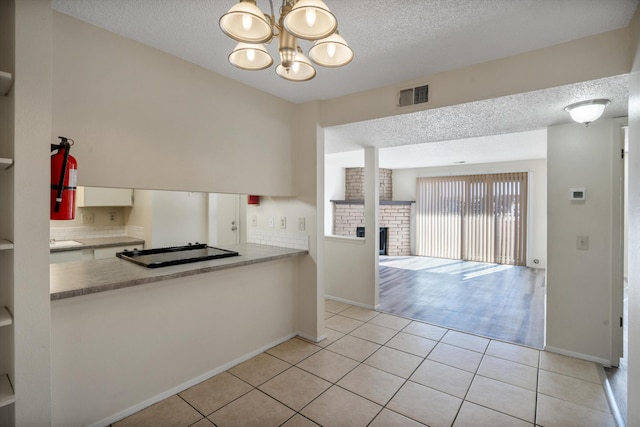 kitchen with visible vents, a notable chandelier, a brick fireplace, and light tile patterned flooring