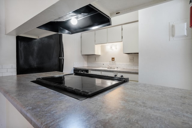 kitchen with white cabinets, freestanding refrigerator, and a sink