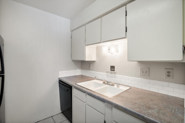 kitchen with light tile patterned floors, a sink, white cabinets, black dishwasher, and a textured ceiling