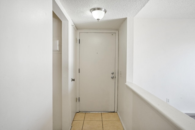 hall with light tile patterned floors and a textured ceiling