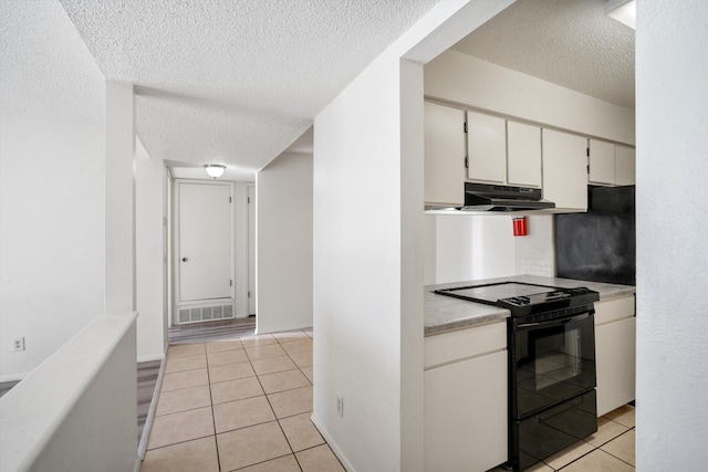 kitchen featuring under cabinet range hood, light tile patterned floors, black / electric stove, and visible vents