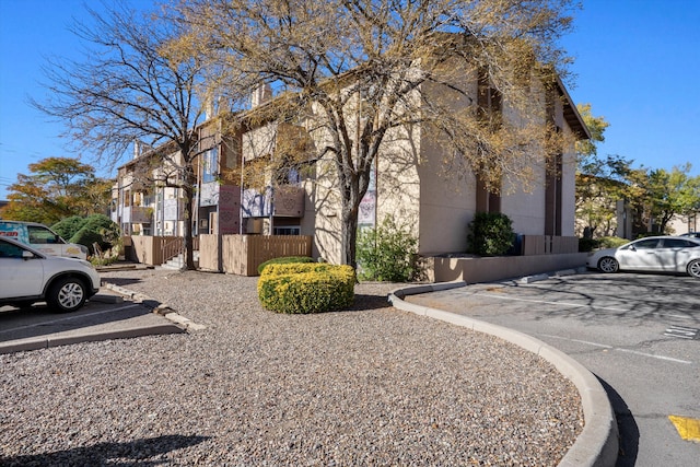 view of home's exterior with a residential view, uncovered parking, and fence